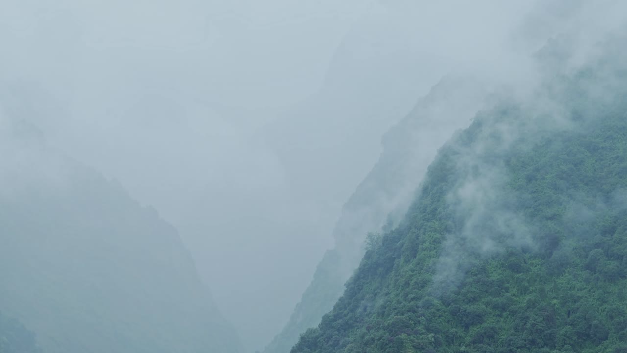 Moody Misty Mountain Background with Copy Space, Blue Layers of Mist in a Steep Mountains Valley Background with Copyspace with Clouds Moving from Above the Trees in an Elevated Aerial View