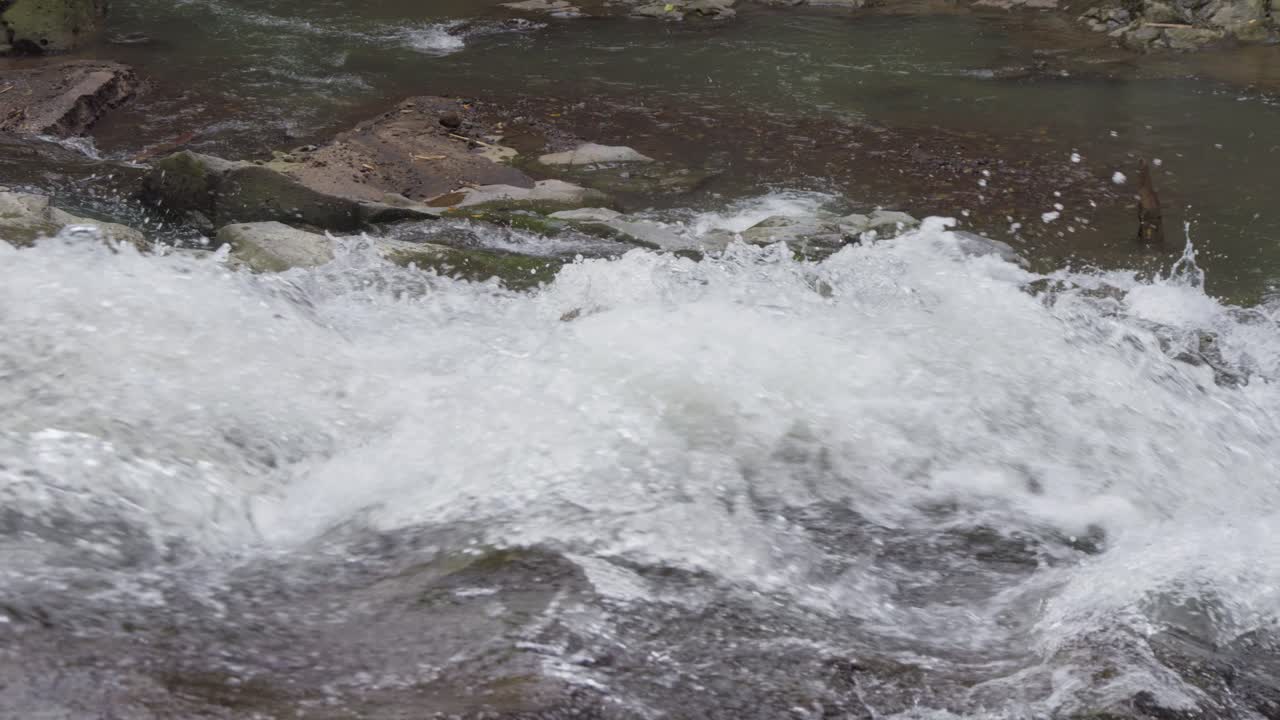 Close-up of bubbling water cascading over the rocks of Goa Rang Reng Waterfall in Bali, Indonesia, captured in slow motion
