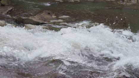 Close-up-of-bubbling-water-cascading-over-the-rocks-of-Goa-Rang-Reng-Waterfall-in-Bali,-Indonesia,-captured-in-slow-motion