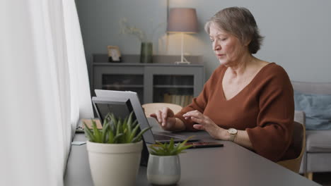 Focused-Woman-Typewritting-At-Laptop-Sitting-At-Desk-At-Home-2