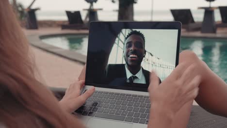 woman wearing white shirt and drinking from a coconut on video call with an coworker while sitting in the hammock in front of the pool in resort 1