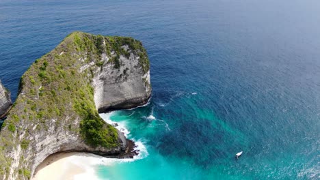 Lonely-boat-moored-near-tropical-coastline-with-blue-ocean,-aerial-view