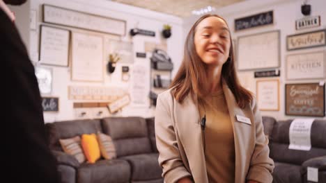 a young female furniture store sales woman shakes the hand of a customer smiles and walks away