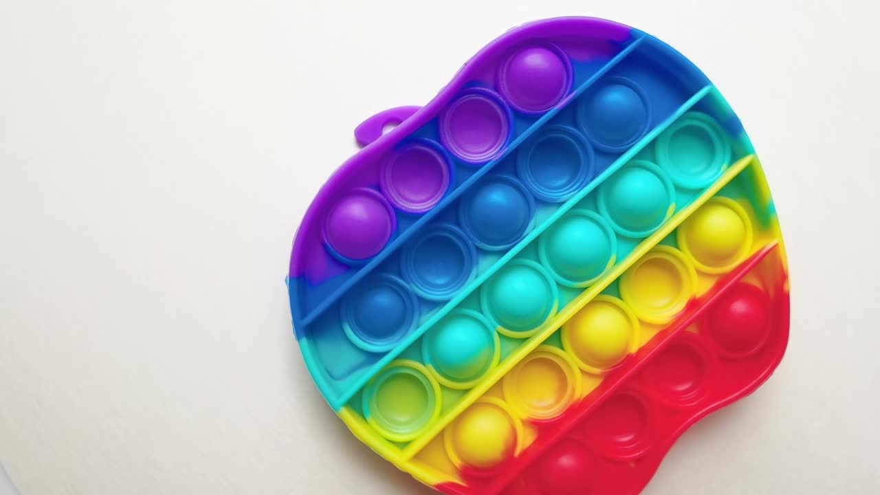 nuevo juguete para bebés. pop it juego de dedos. color gracioso. colorido juego girar en la mesa blanca. forma de manzana arco iris