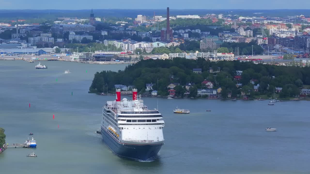 Fred.Olsen Cruise Lines passenger ship BOREALIS making way ahead in Finnish archipelago on departure. City skyline in background. Distant high altitude aerial front view.