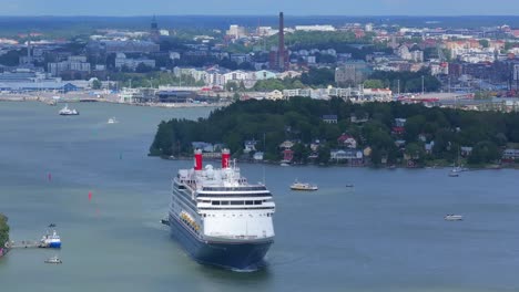 fred.olsen cruise lines passenger ship borealis making way ahead in finnish archipelago on departure. city skyline in background. distant high altitude aerial front view.