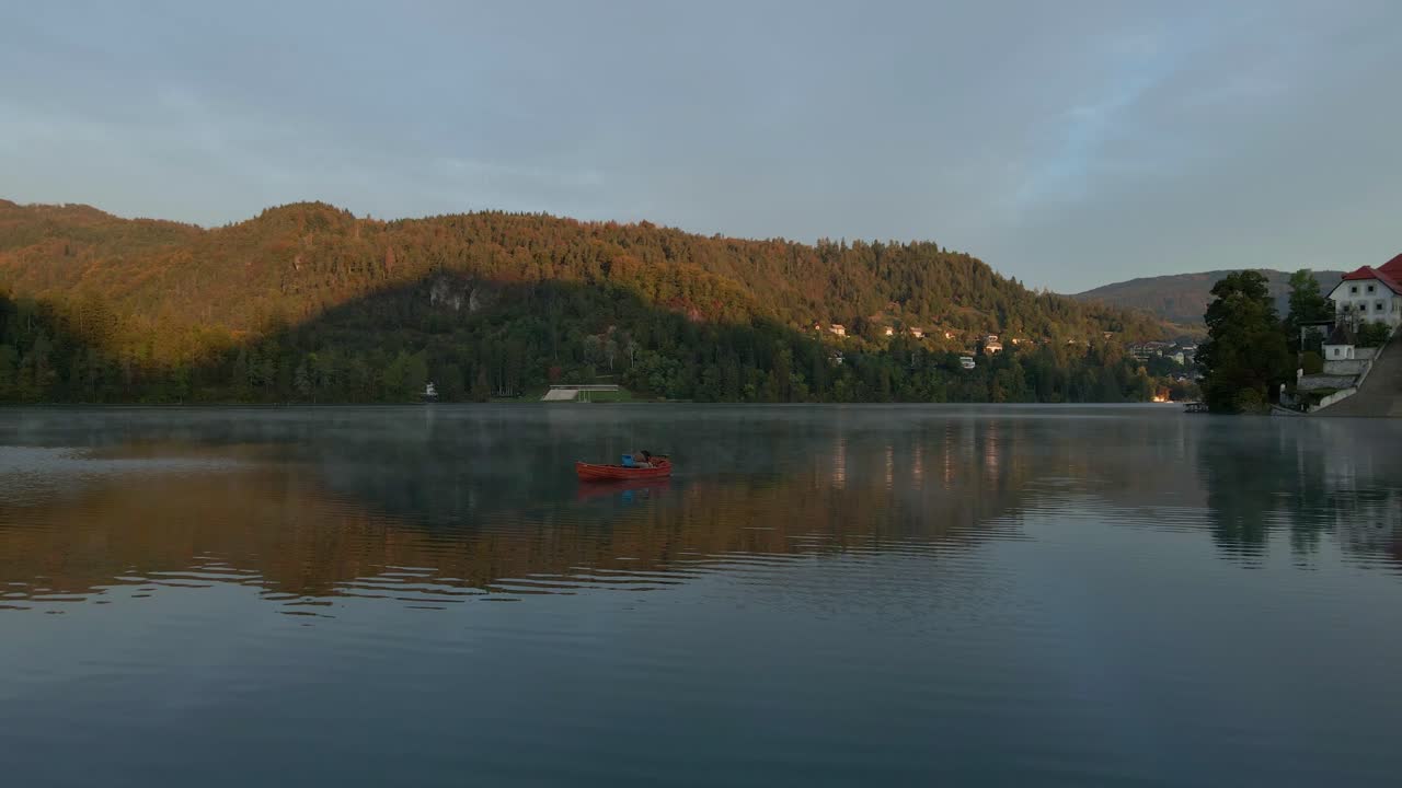 Tranquillo Lago di Bled con chiesa sull'isola e barca all'alba