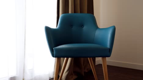 slow orbiting shot of a blue chair sitting beside the window in a hotel room