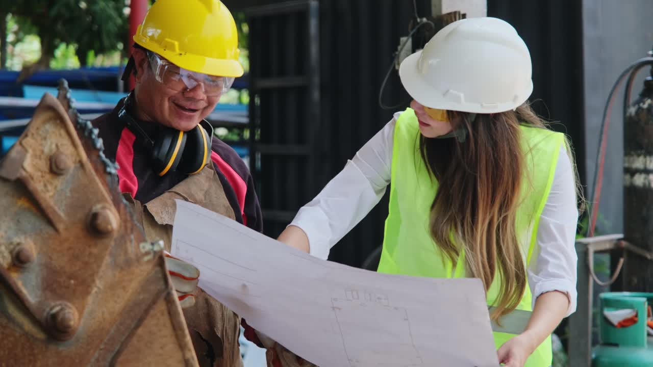 gerente de ingeniería asiático y trabajador mecánico trabajando en un casco mientras discuten e inspeccionan el proceso de fabricación en la fábrica.