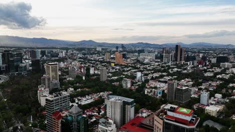 Ascending-aerial-view-of-the-cityscape-of-Mexico-city,-on-a-partly-sunny-evening