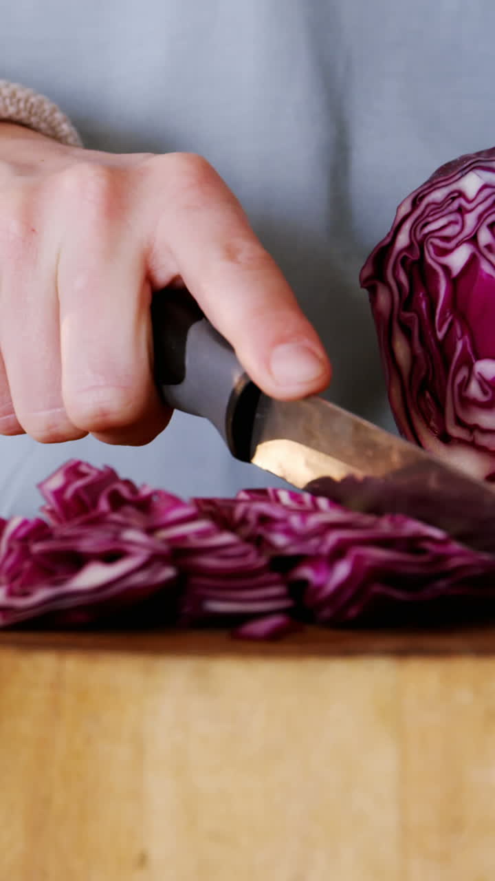 Metà di sezione della donna che taglia cavolo rosso in cucina