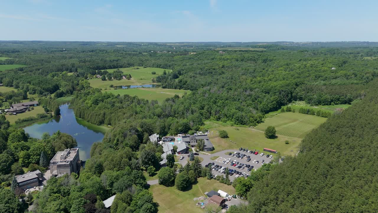 Aerial flyover of Millcroft Inn and Spa surrounded by trees, stream, and landscaped paths