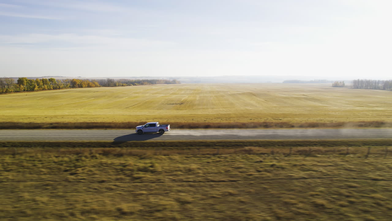 Pickup Truck Driving On The Dusty Road Along The Countryside Fields. - aerial shot