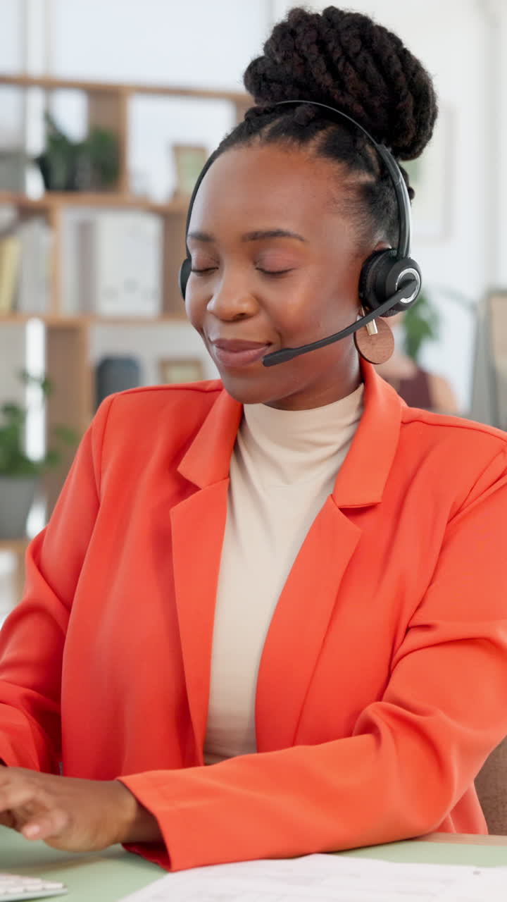 Donna di colore felice che indossa un auricolare e parla in ufficio.