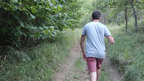 Un-Hombre-Camina-Por-Un-Sendero-En-El-Bosque,-Durante-El-Día,-Temporada-De-Verano