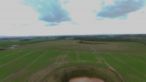 flight across fields with camera facing down and tilting up to look forward as it passes over ponds and fields. the pond has flooded the farmland making it waterlogged