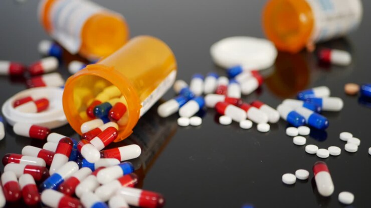 Many prescription pills, drugs and antidepressants spilling in slow motion from an orange pharmacy medicine bottle SLIDE RIGHT