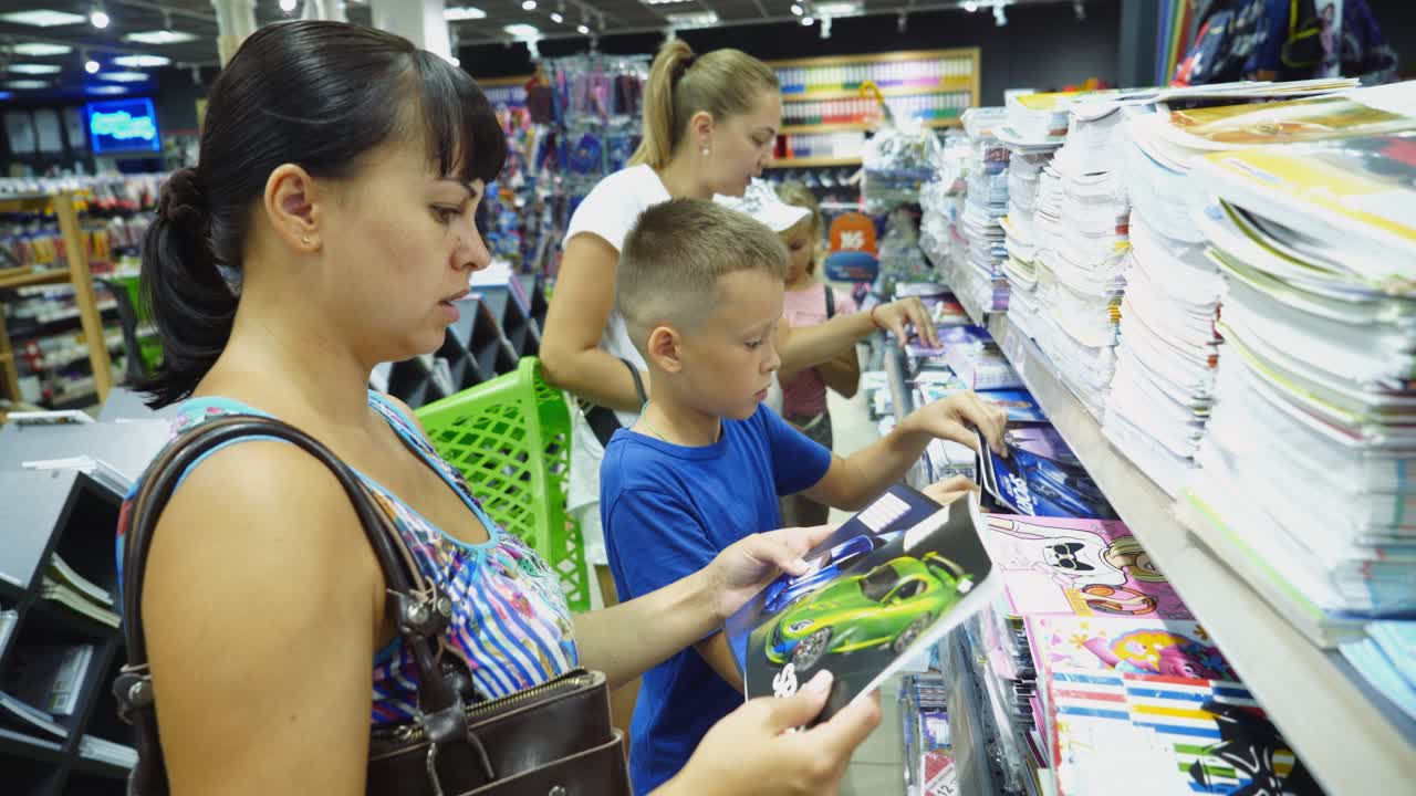 VINNITSA, UKRAINE - AUGUST 20, 2018: Back to school concept. Young mother and little boy buying school supplies in store.