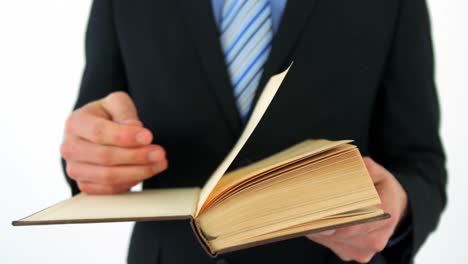sección media de un hombre de negocios volteando páginas de un libro