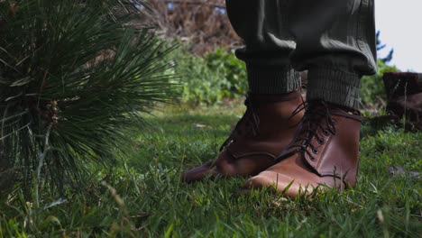 Female-hand-picks-up-axe-with-leather-shoes-and-pine-tree