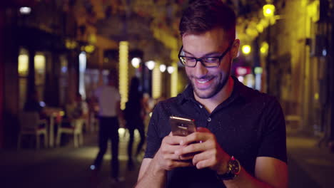 hombre sonriendo mientras usa el teléfono inteligente en