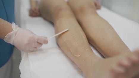 beautician applies laser hair removal gel on legs. female client makes laser hair removal procedure in modern spa centre