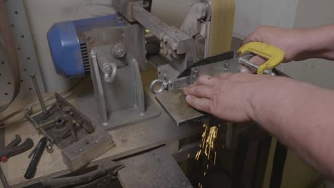 craftsman sharpening knife blade on professional grinder lathe in workshop