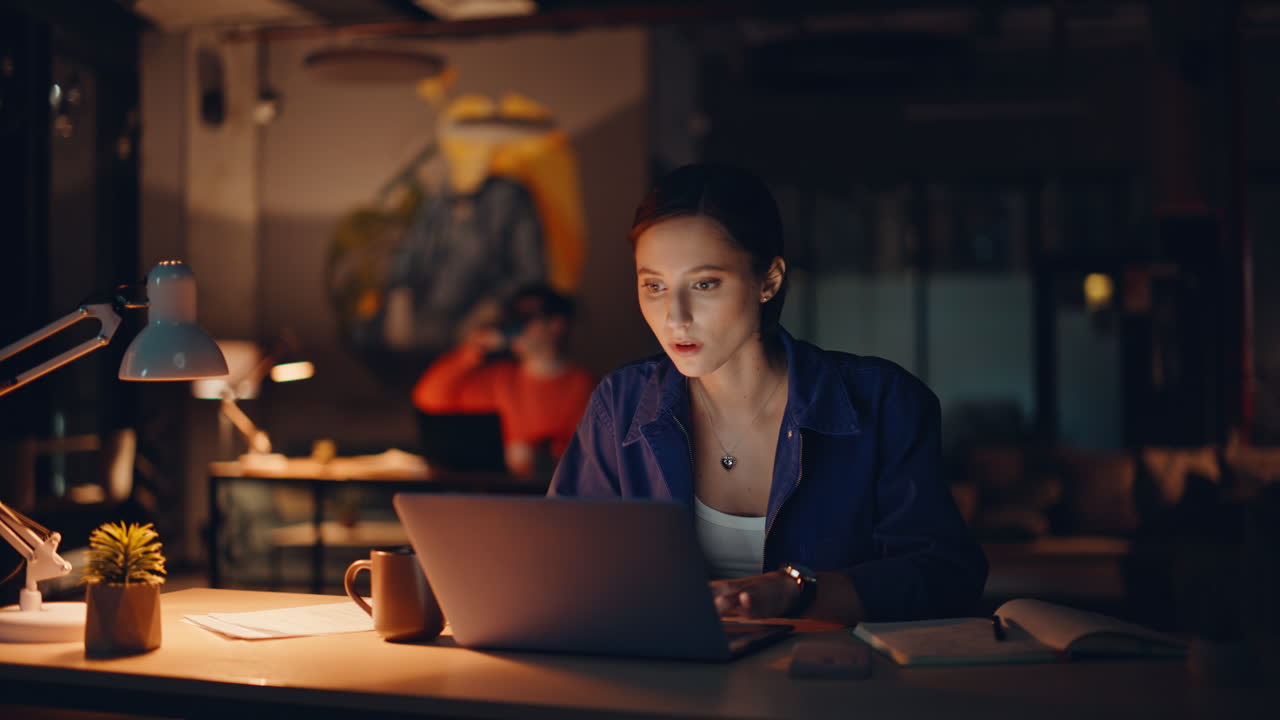 Primo piano di un lavoratore notturno che sviluppa un progetto facendo gli straordinari e bevendo caffè in un ufficio buio