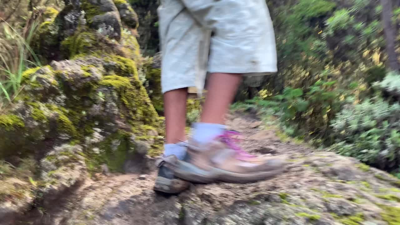Vista posteriore di gambe maschili nere che scalano pietre nella roccia passo dopo passo