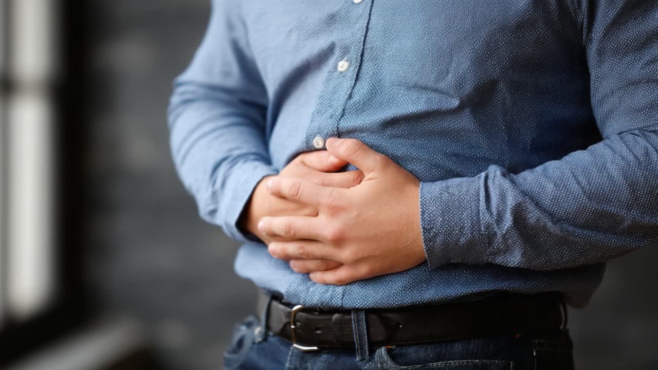 Uomo che si tiene lo stomaco per il disagio, mostrando segni di dolore o sofferenza, evidenziando problemi di salute e possibili problemi digestivi, riflettendo malessere fisico