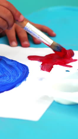 cute little boy painting at table in classroom