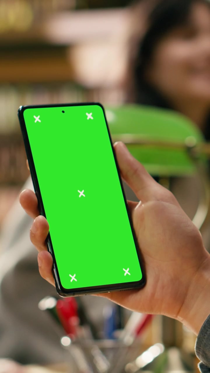 Video verticale. Mockup a schermo verde verticale su telefono tenuto in mano durante una sessione di studio.