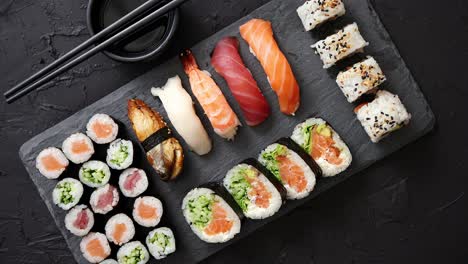 sushi rolls set with salmon and tuna fish served on black stone board