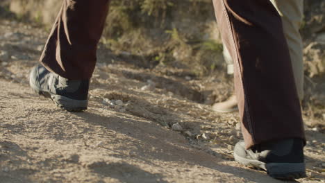 close up shot of two unrecognizable people hiking and walking along a dirt road