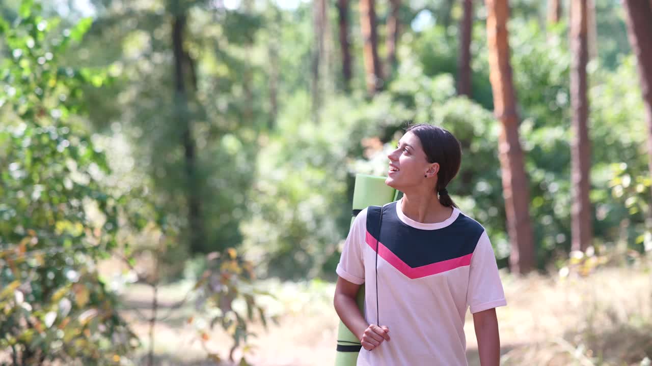 요가 매트 를 들고 숲 에서 산책 하는 소녀