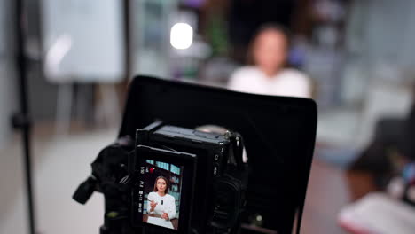modern camera filming a brunette woman. close up high-angle view on the equipment used at blog content creation. blurred backdrop.
