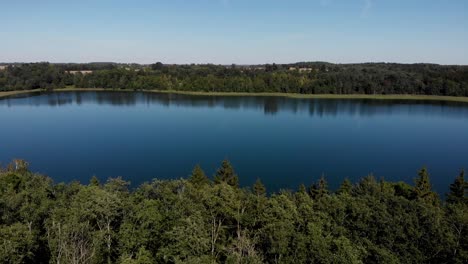 dron volando por encima de los árboles hacia un gran lago hermoso