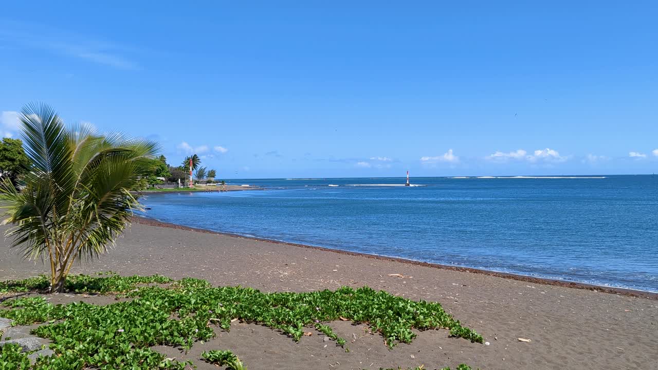 Scenic landscape view of black sandy beach and blue ocean water in Papeete, Tahiti, French Polynesia