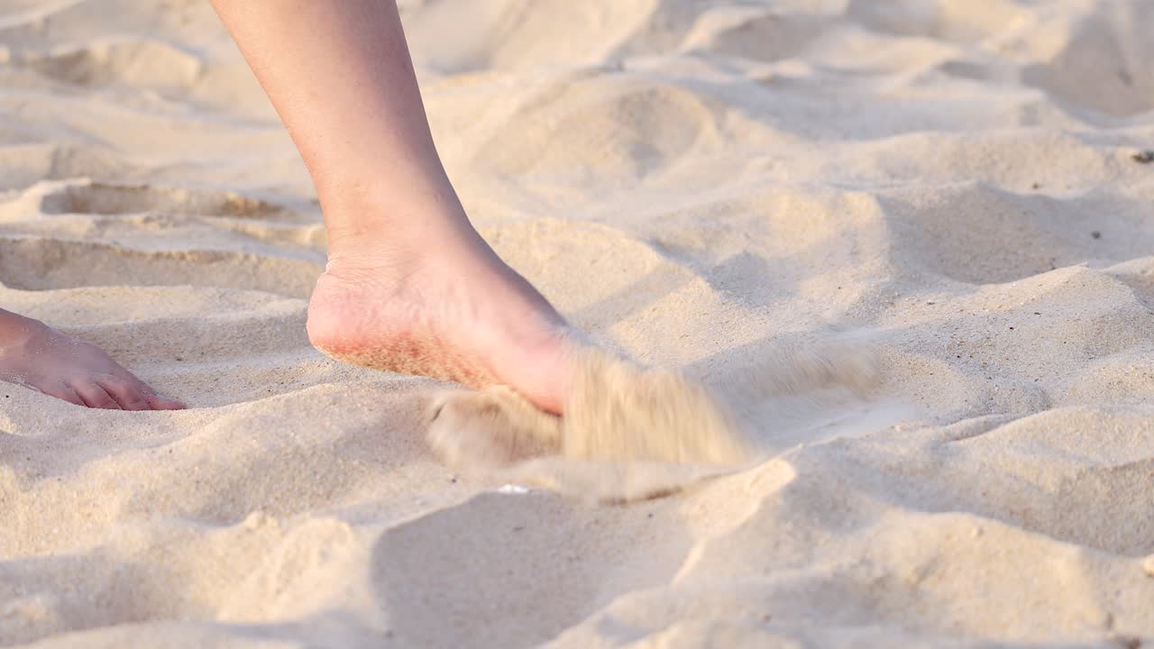 Person walking barefoot kicking sand on Karon Beach, Phuket, Thailand