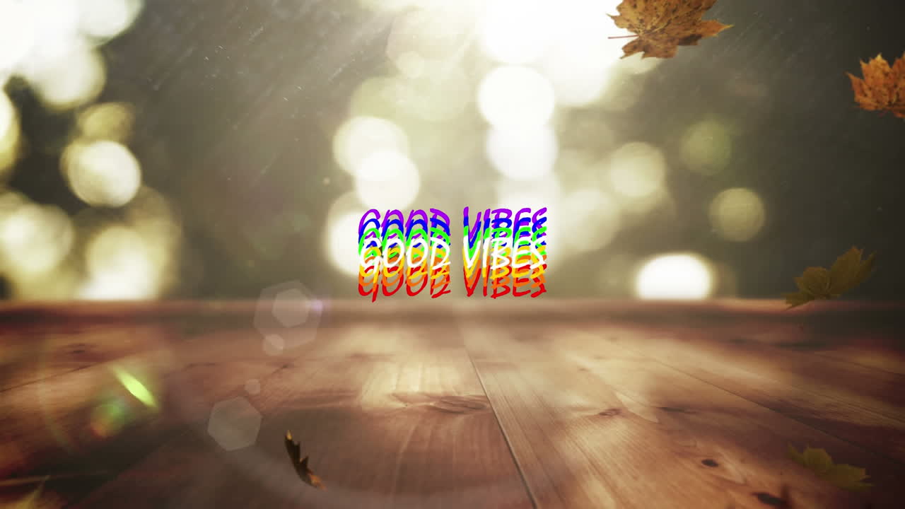 Animation of the words good vibes in rainbow letters over falling autumn leaves and bokeh sunlight