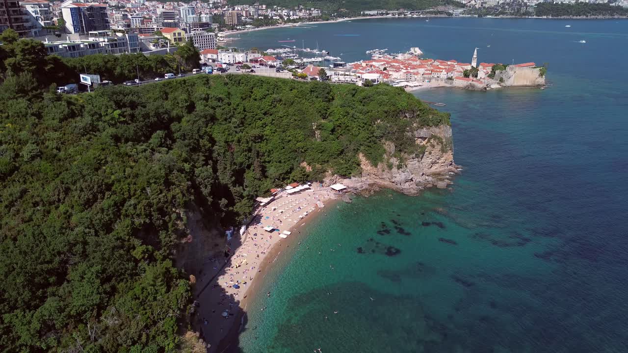 Spiaggia affollata vicino alla vecchia Budva con panorama urbano sullo sfondo sulla costa adriatica, vista aerea panoramica