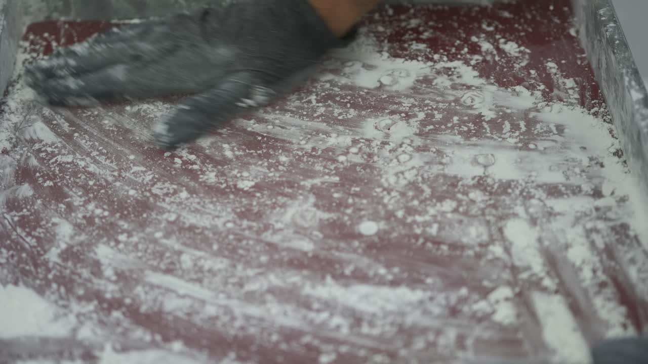 Close-up of a tray of cooked Turkish Delight at the factory as a worker spreads flour over the top before the machine chops it into squares