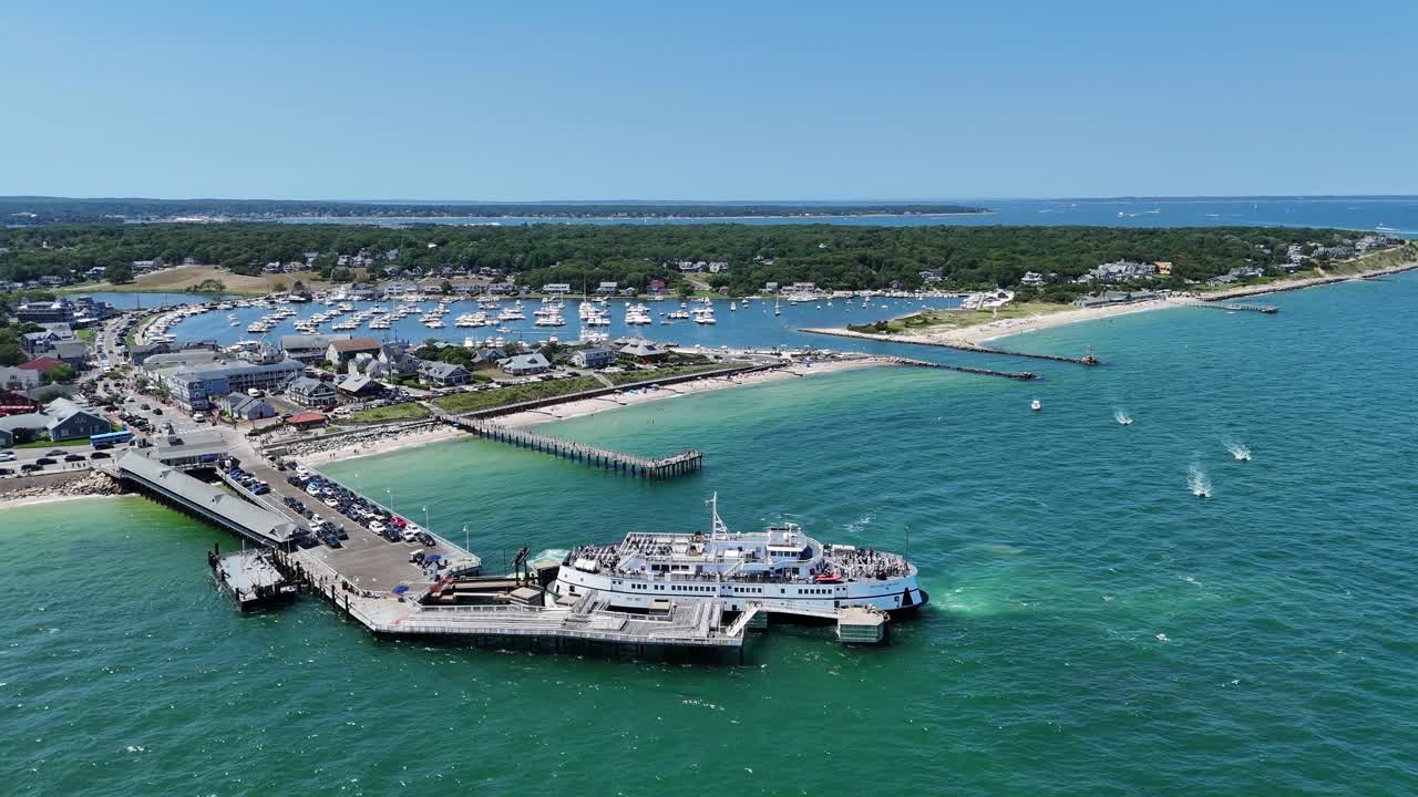 Vista aerea con drone del porto di Martha’s Vineyard nella Contea di Dukes, Massachusetts, con traghetto attraccato al molo, acque oceaniche turchesi, porto turistico con barche e pittoresca città costiera in una soleggiata giornata estiva