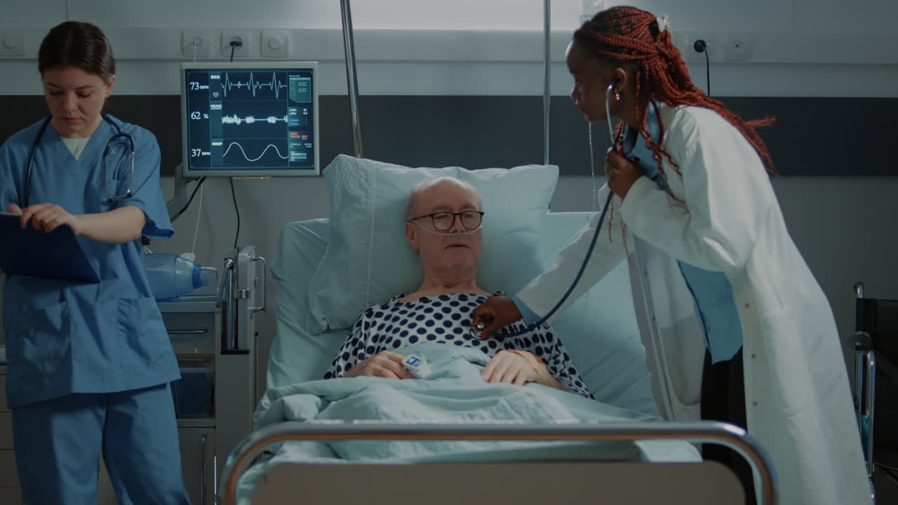 Multi ethnic personnel treats patient in hospital ward