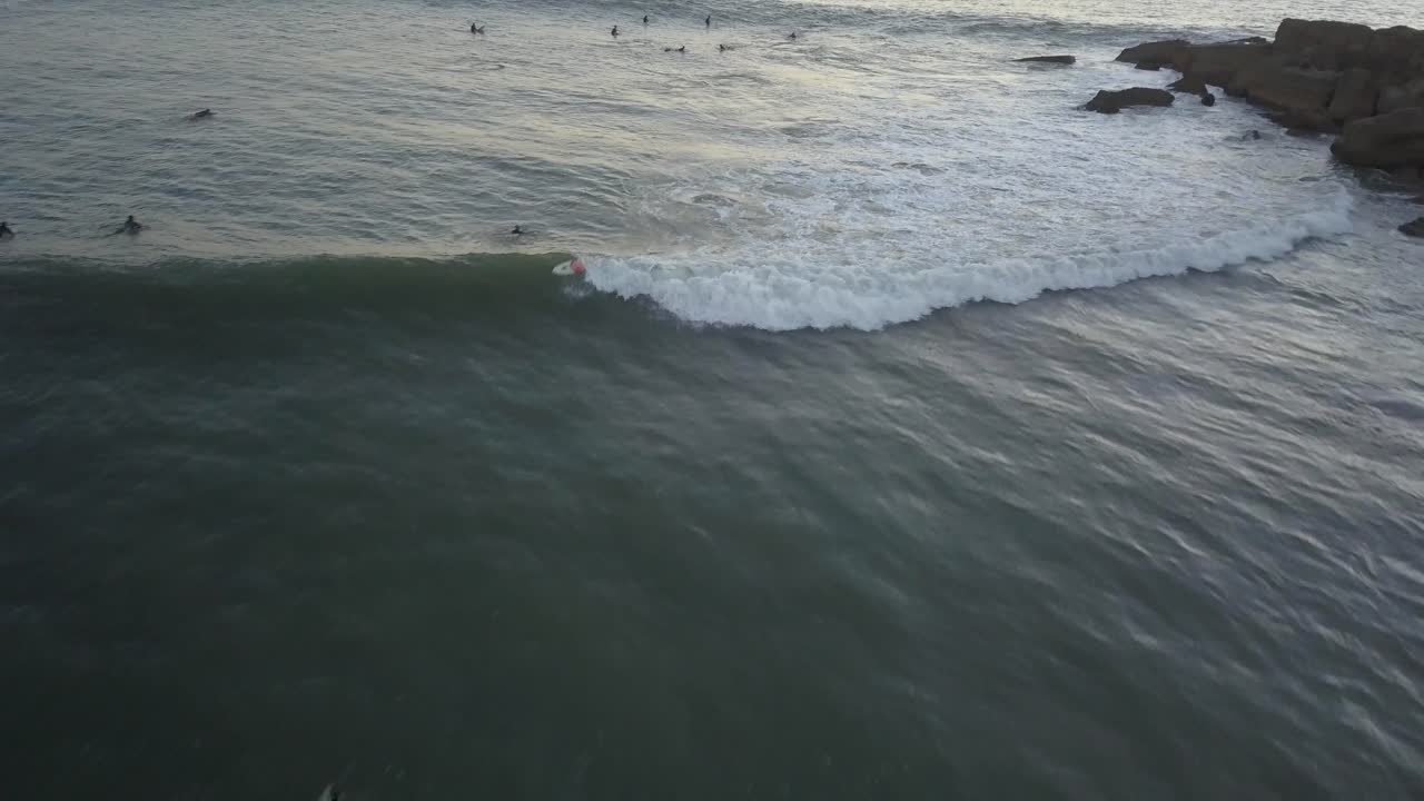 At sunrise, a solitary wave breaks at the S&atilde;o Pedro peak in Estoril, Cascais, with surfers waiting eagerly in the outside lineup for their turn to ride