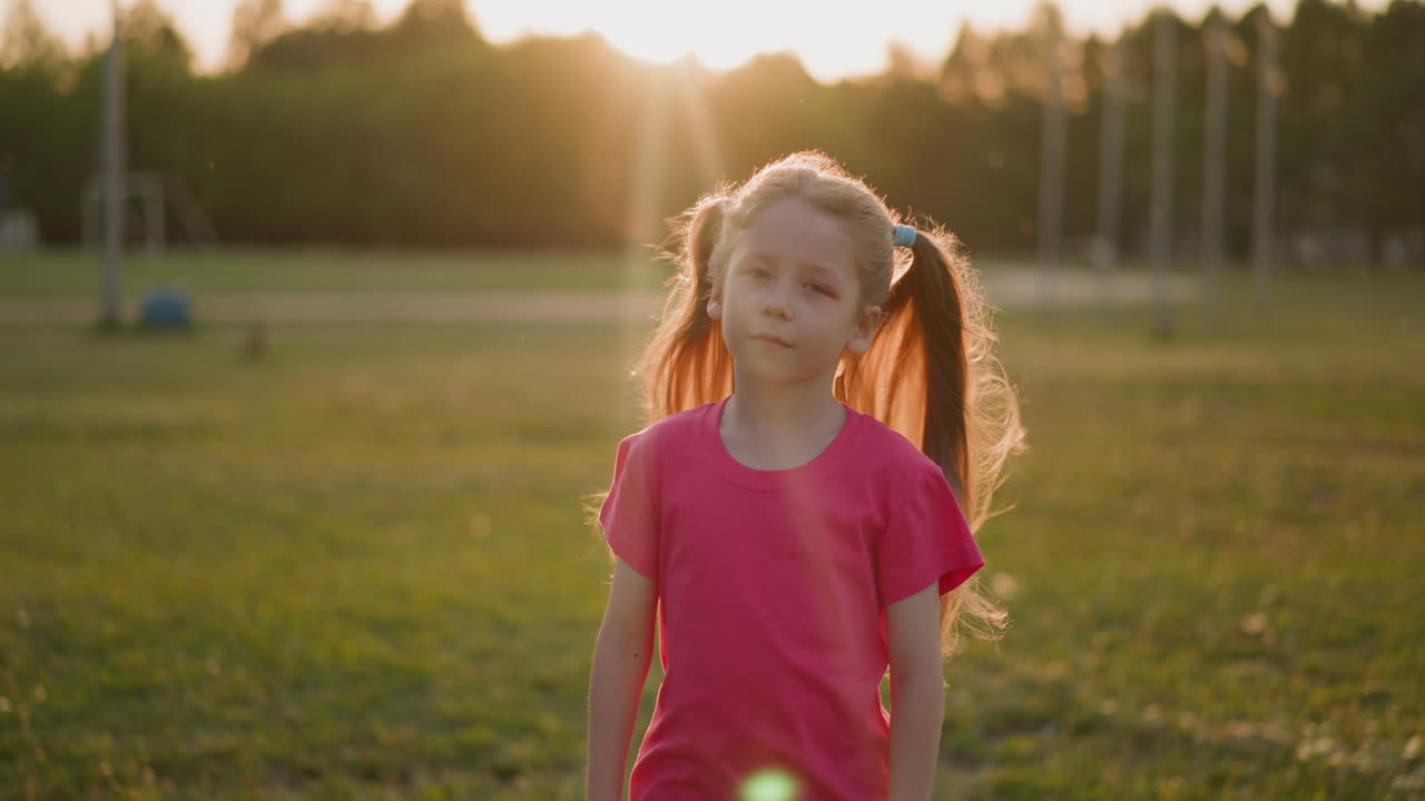 금발 포니테일을 가진 귀여운 작은 소녀가 초원에서 돌아갑니다.