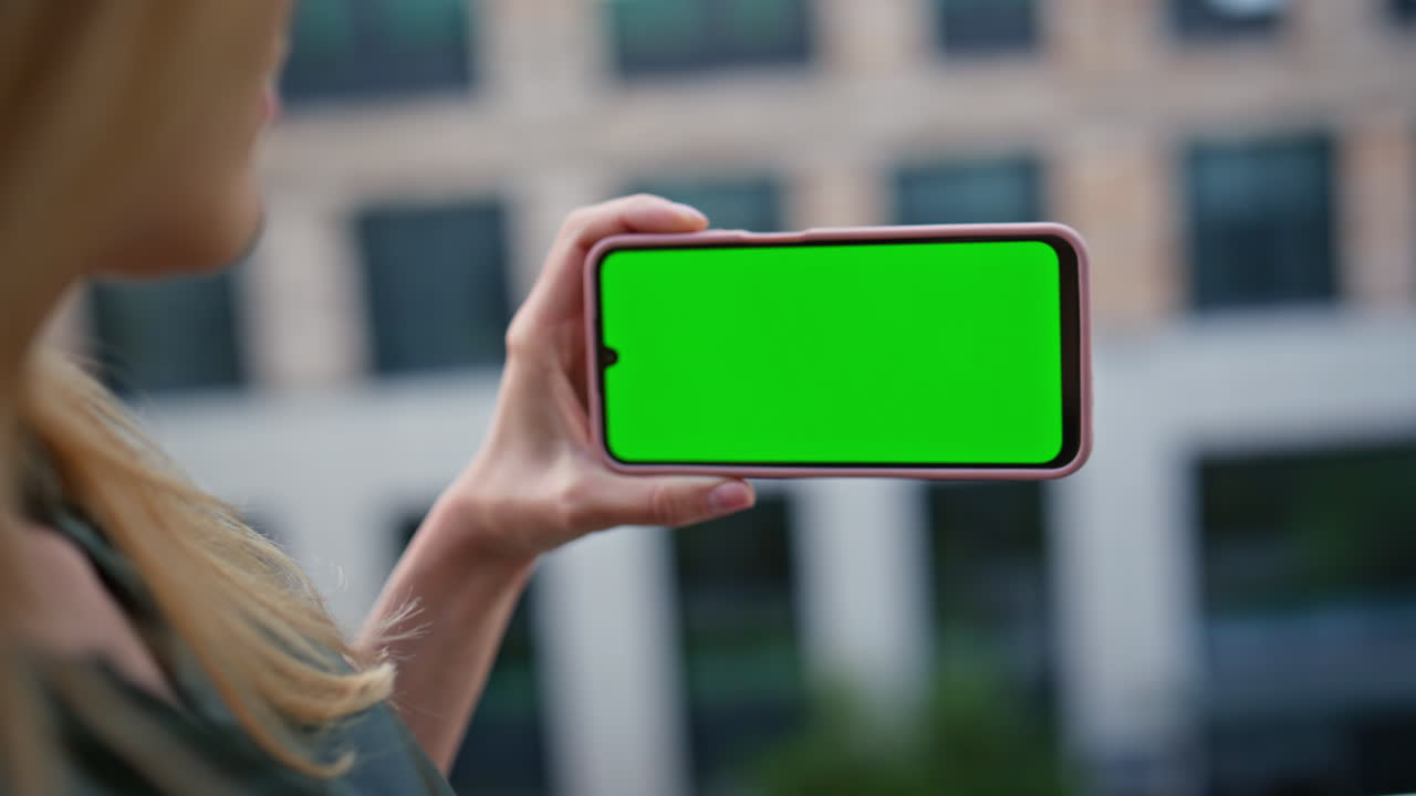 Hand tapping greenscreen smartphone in district closeup. User touching phone