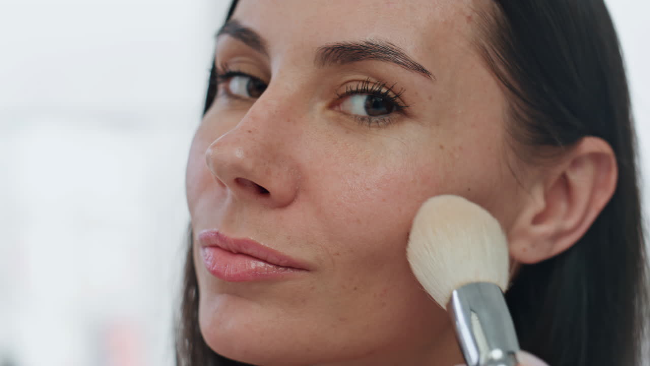 Ritratto di modella che applica la cipria a casa. Donna sorridente che applica il fard, si trucca