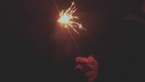 bright festive christmas sparkler in hand in the night, vintage toning slow-motion