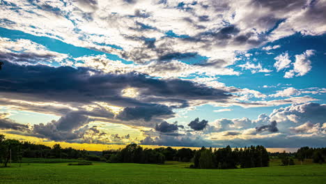 Cinematic-time-lapse-of-fast-moving-clouds-over-a-grassy-landscape-with-trees-with-the-sun-shining-through-the-clouds-on-a-beautiful-day